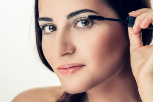 Woman applying mascara on her long eyelashes